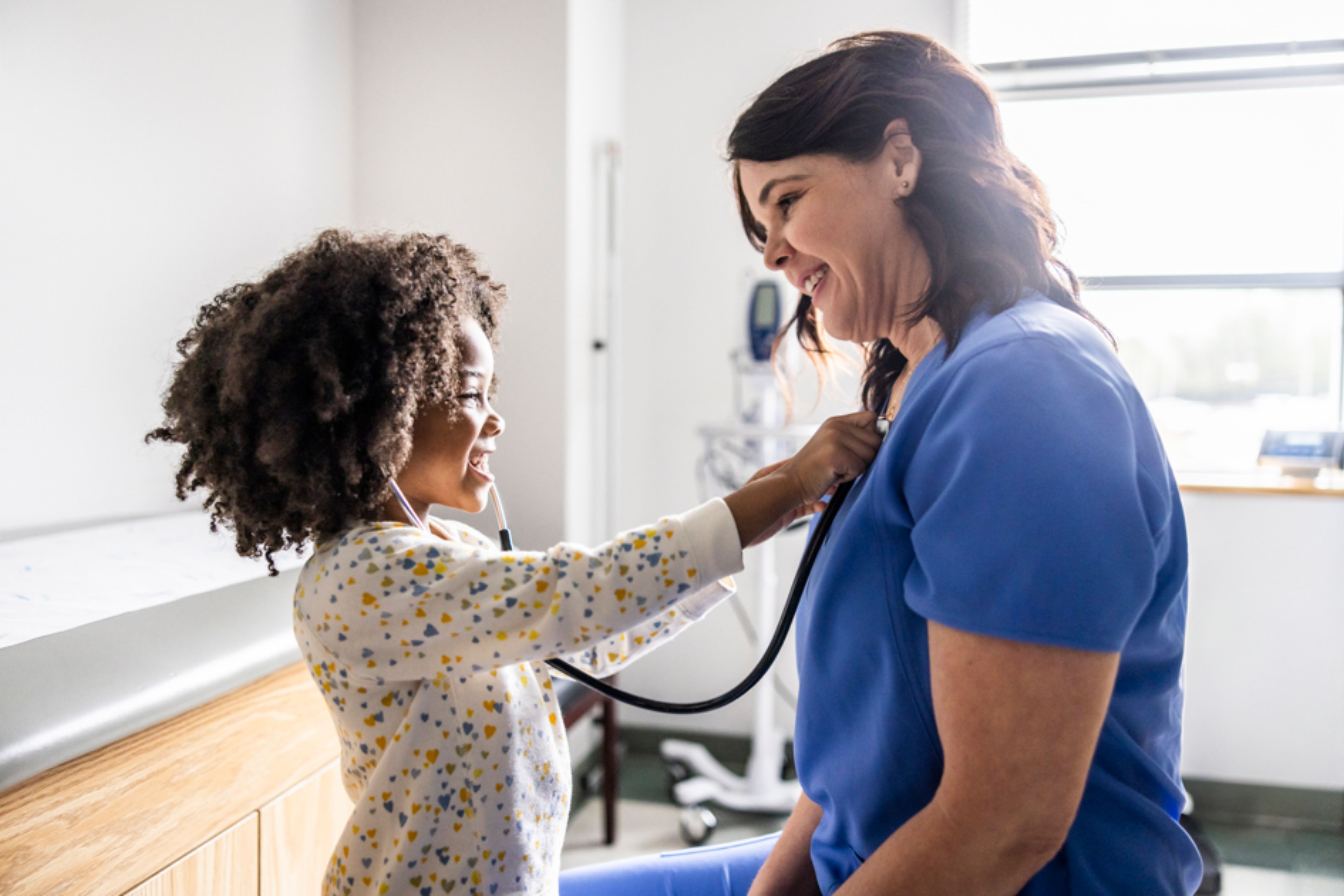 Enfant interagissant avec une soignante en cabinet m&eacute;dical, illustrant la relation de soin dans les &eacute;tablissements accompagn&eacute;s par Forvis Mazars