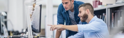 An image of two colleagues looking at a computer screen in an office