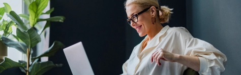 Wealthy woman wearing glasses sitting down on laptop at home, working on business and finances.