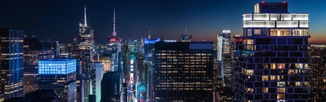 This high angle night view from Midtown Manhattan looks south over Broadway toward Times Square. Some of the buildings seen here are 745 Seventh Avenue, Bank of America Tower, 4 Times Square, Paramount Plaza and 242 West 53rd Street. One World Trade Center can be seen in the distance.