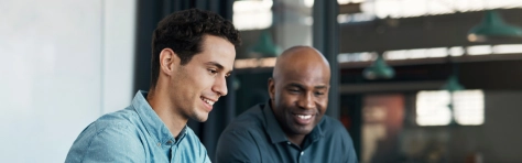 Deux collaborateurs souriants en réunion de travail, illustrant l'accompagnement en gestion sociale et paie