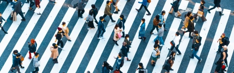 Birds eye view, aerial photo of busy crossing in city centre and commercial district. Zebra crossing with lots of commuters and professionals cross the road.