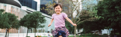 Image of a little girl running on a lawn in park joyfully