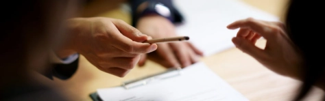 una mano che passa la penna ad una altra mano per firmare un documento