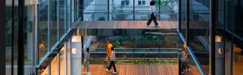Interior of a modern building with glass walkways and people walking between floors.