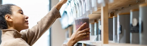 ragazza che versa dei cereali da un dispender in un bicchiere grande di plastica