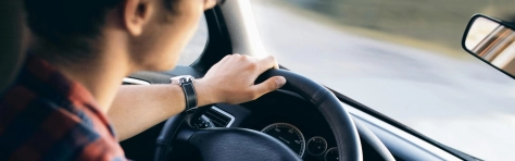 Man sitting inside car driving with hands on steering wheel. Commuter driving to work and home.
