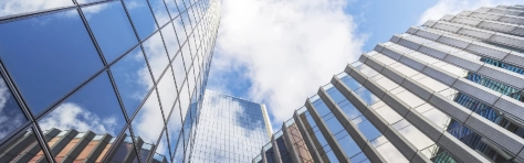 UK, looking up at modern glass and steel built office buildings in London business district with cumulus clouds overhead
