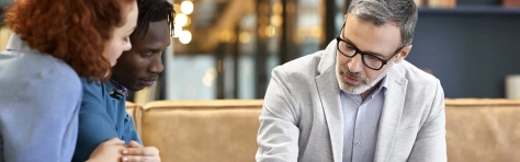 Advisory meeting on individual taxation between a tax advisor and clients reviewing financial information on a tablet.