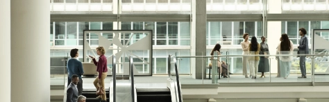 GettyImages-2199581608 Modern architecture, Escalators, People walking, Indoor space, Large windows, Multi-level, Urban design, Glass walls, Building interior, Busy environment, Open layout