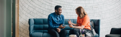 Businessman and woman talking while sitting on couch