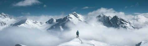 uomo su una montagna piena di neve che guarda altre montagne davanti a lui