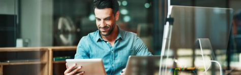businessman con in mano un tablet davanti a un pc