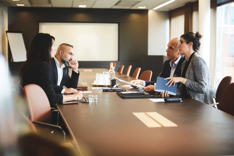 Forensic services professionals in a serious discussion across a boardroom table