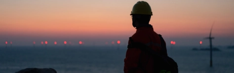 An image of an engineer enjoying the beautiful scenery of a wind farm by the sea