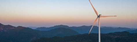 An image of a wind turbine in the hills generating energy.