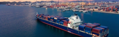Cargo ship with shipping containers boarding a coastal port by the sea.