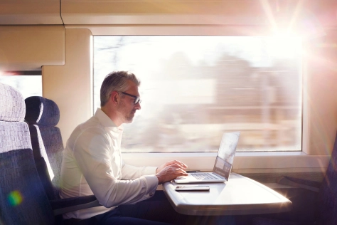 Man sitting in the train looking to the laptop