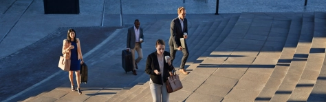 Businesspeople walking with bags on staircase outside