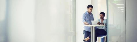 Due colleghi che guardano ad un computer su un tavolino in una stanza bianca