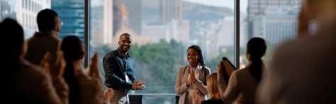 Conference, Celebrating the success of the company, Innovation pitch, Applause from the audience in the room, Office setting, Buildings in the background, Standing ovation, Meeting room, Business presentation