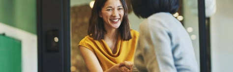 donna frontale che stringe la mano ad una donna di spalle