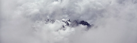 vetta di una montagna che esce dalle nuvole che riempiono il cielo