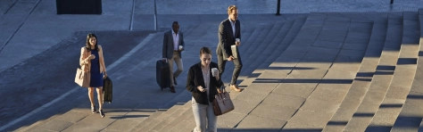 Businesspeople walking with bags on staircase outside, at sunrise