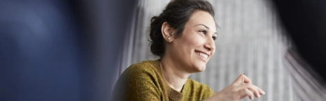 businesswoman che guarda davanti a sè sorridendo con un maglione giallo