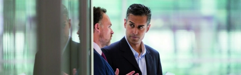 due businessman che parlano camminando accanto ad un vetro