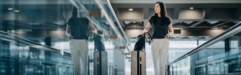 Professional travelling through a modern airport terminal with luggage, representing international mobility and cross-border workforce movement.