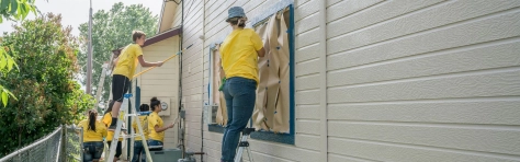 An image of a group of people doing volunteer/ charity work. They are painting houses.