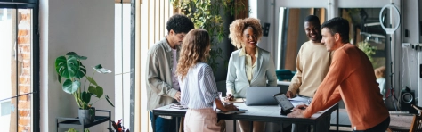A group of colleagues talking while standing at the office desk