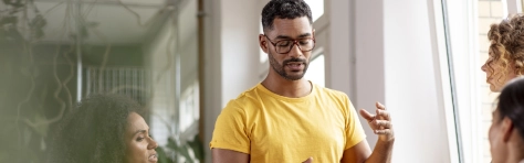 Man in yellow t-shirt having a meeting together with colleagues and employees in the office.