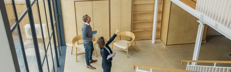 A Female property agent showing man around empty office space