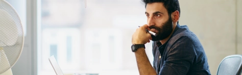 An image of a man in an office sitting down and thinking