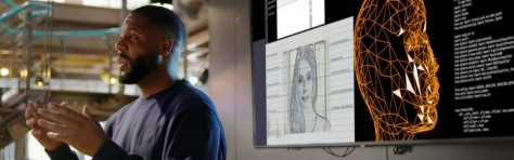 uomo spiega con alle spalle una tv con dei contenuti di intelligenza artificiale