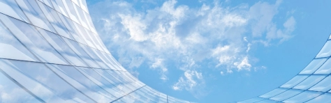 Abstract architecture with large glass surfaces shaped in a large curve and reflecting the blue sky. Modern, futuristic architecture with ethereal design. Looking up at the bright sky: tranquility, meditation.