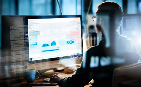 Man sitting behind the desk with computer and looking at the graphs