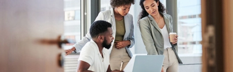 An image of three professional colleagues reviewing a piece of documentation in an office.