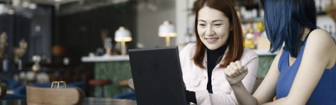 two people looking at a laptop in a cafe