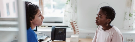 Image of two women sitting down and discussing something within an office setting 