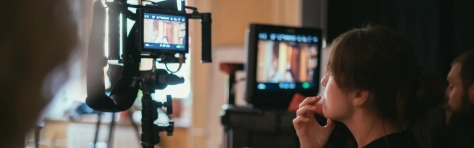 Businesswoman and businessmen discussing during online seminar, sitting on armchairs on the stage. Focus on video camera.