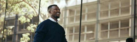 Fashion, travel and corporate employee or businessman traveling and walking out of a building or airport in a city. African American worker or traveller in an urban town with good style going to hotel