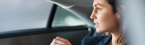 An image of a businesswoman looking out a car window thinking 