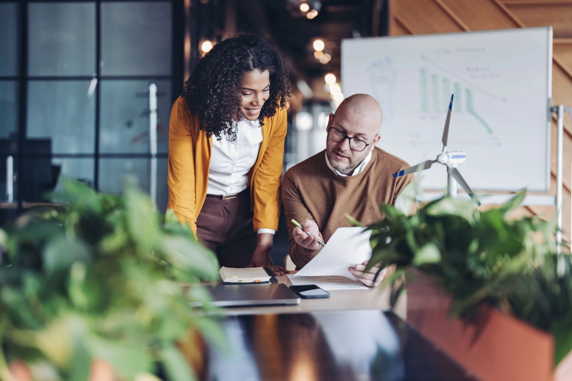 Two professionals reviewing sustainability and business performance data in an office.