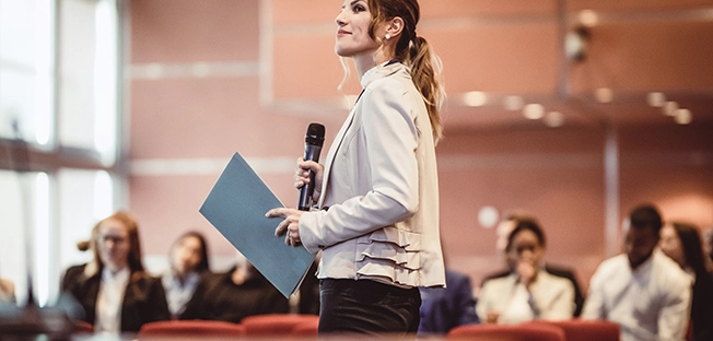 f6f843ac17fd-speaker-in-front-of-audience.jpg.webp f6f843ac17fd-speaker-in-front-of-audience.jpg.webp