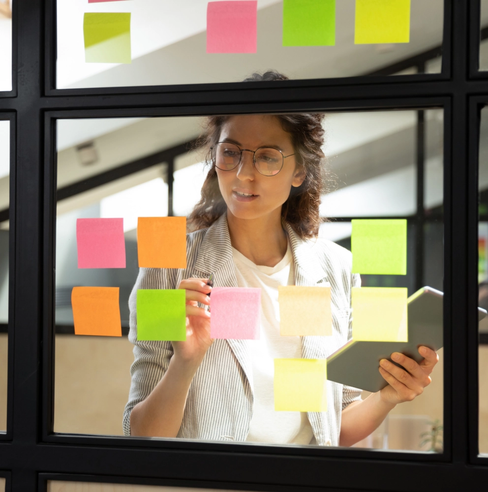 Management consulting. Pessoa em primeiro plano com tablet na mão olhando para post its