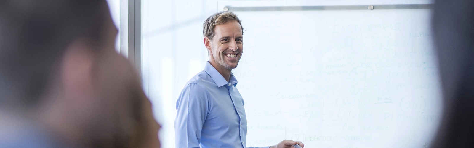 Happy businessman giving presentation to colleagues. Male professional is making strategies in board room. He is standing by whiteboard in office. Presentation - Speech Business Whiteboard - Visual Aid Business Meeting Discussion Office Meeting Happiness Business Conference Copy Space Smiling Brainstorming 45-49 Years Cooperation Creative Occupation Focus On Background Mature Adult People Professional Occupation