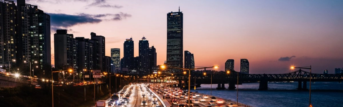strada piena di macchine con sullo sfondo uno skyline al tramonto